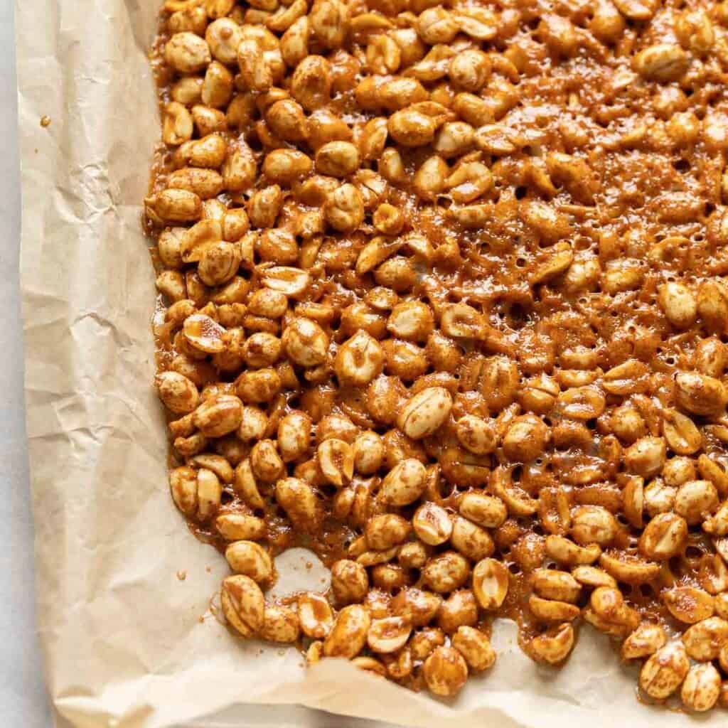 Honey roasted peanuts still on the parchment paper lined baking try after baking