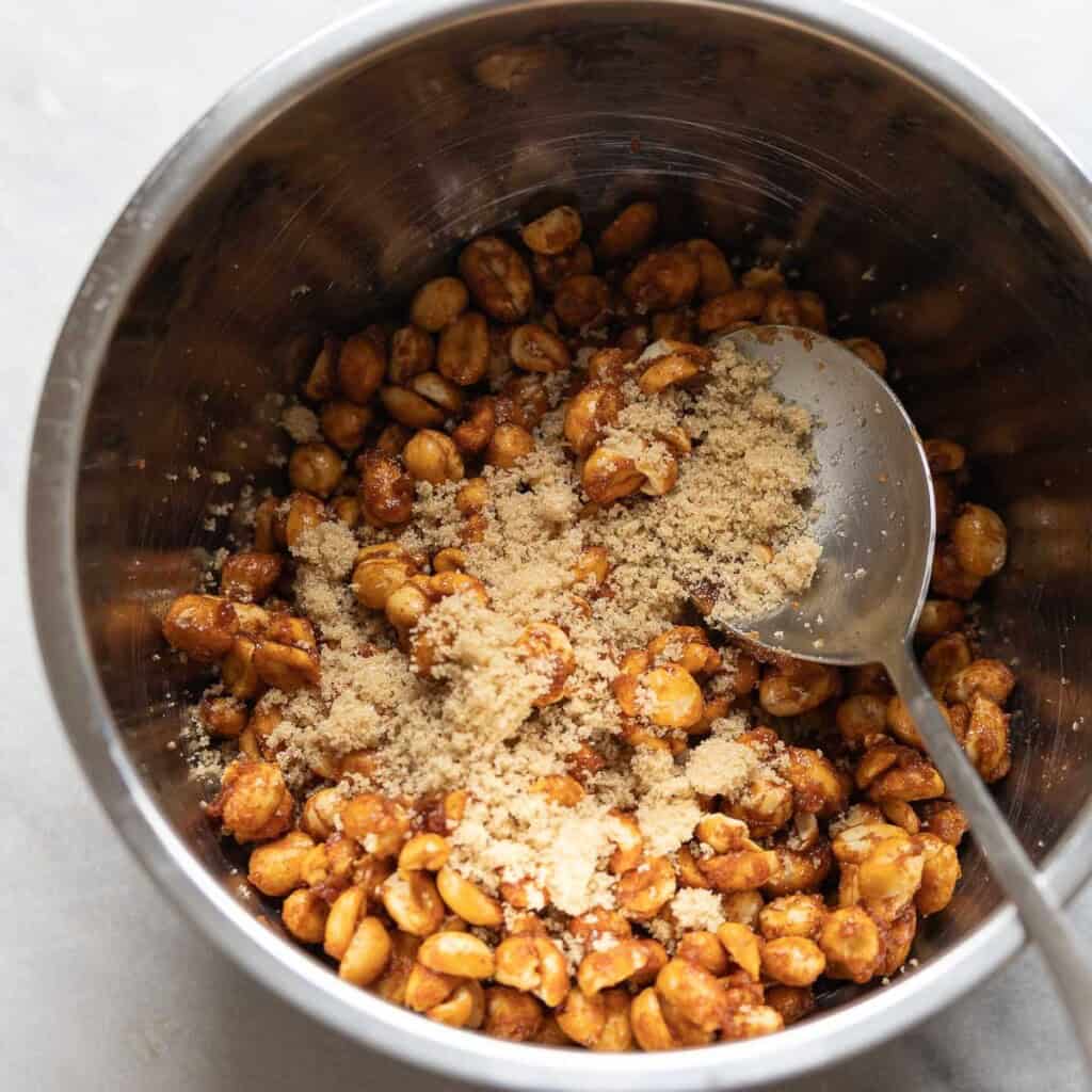 Light brown sugar and salt tossed on top of Honey roasted peanuts in a large mixing bowl
