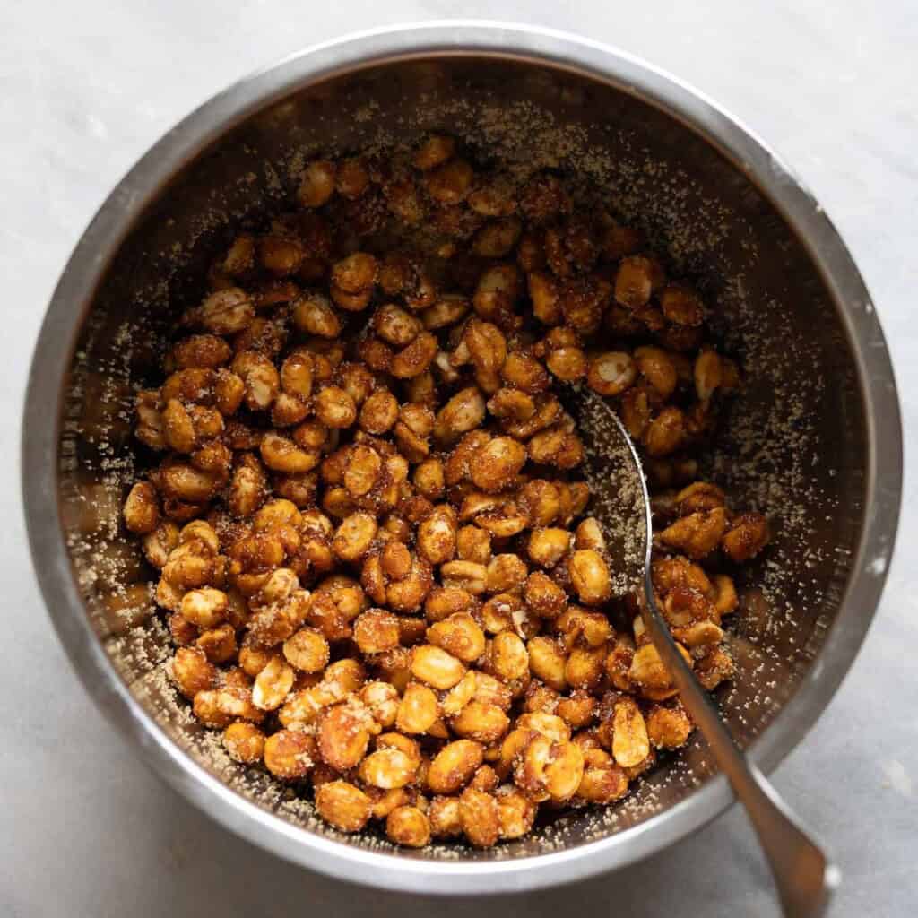 Honey roasted peanuts tossed in a large mixing bowl with salt and brown sugar