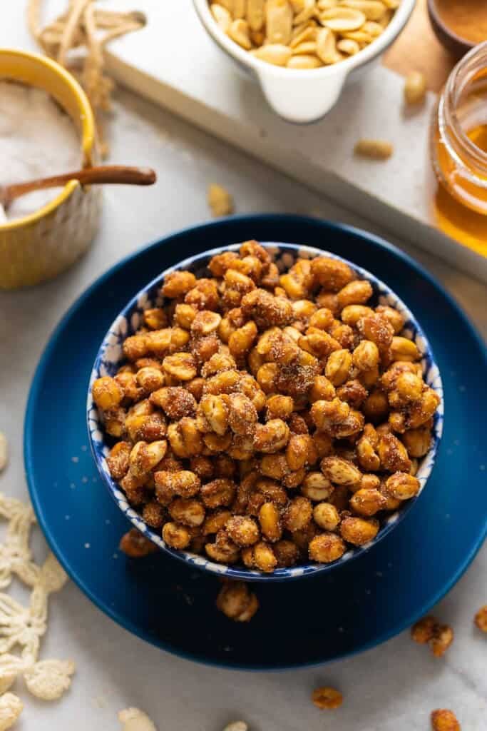 Honey Roasted Peanuts in a serving bowl with some of the whole ingredients surrounding the bowl