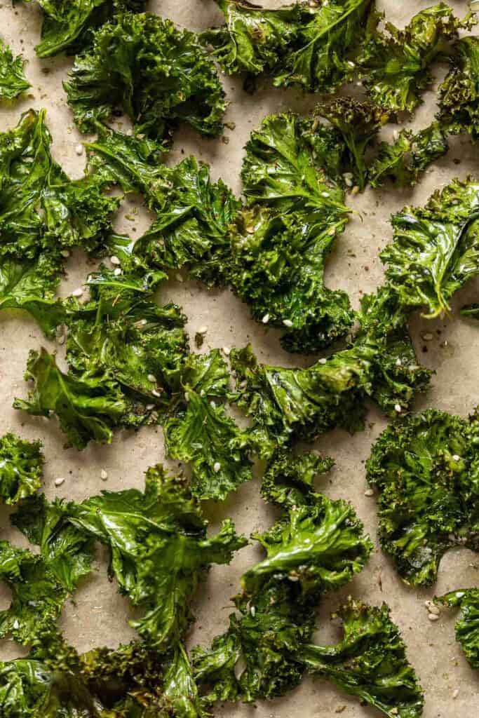 Baked kale chips seasoned with salt, pepper and za'atar spice spread out on a baking sheet