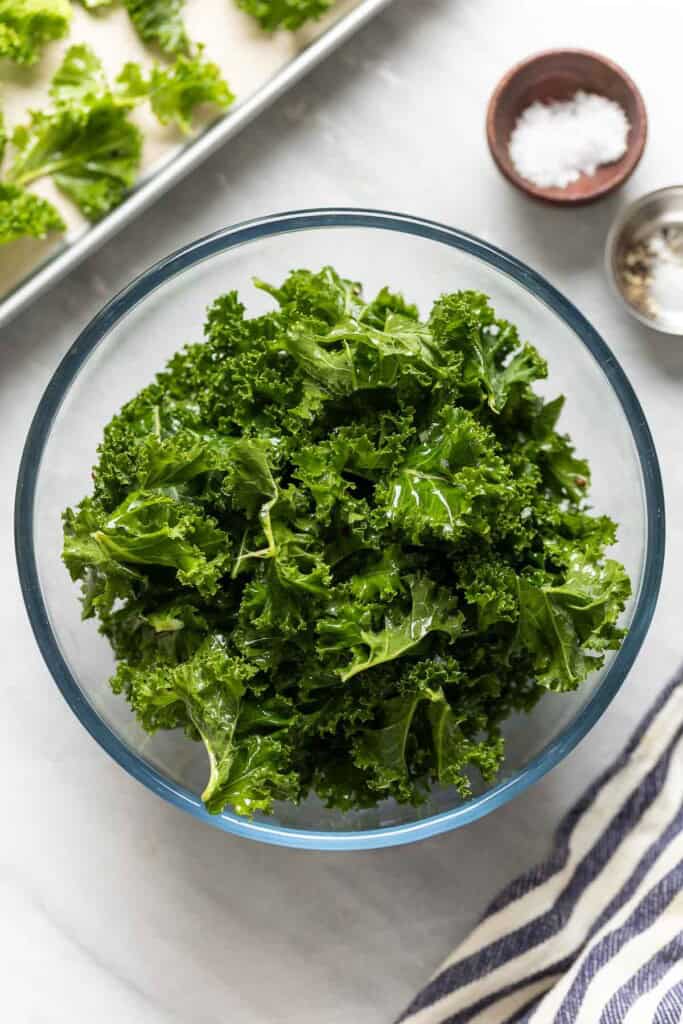 Raw kale in a bowl tossed with oil, salt and pepper