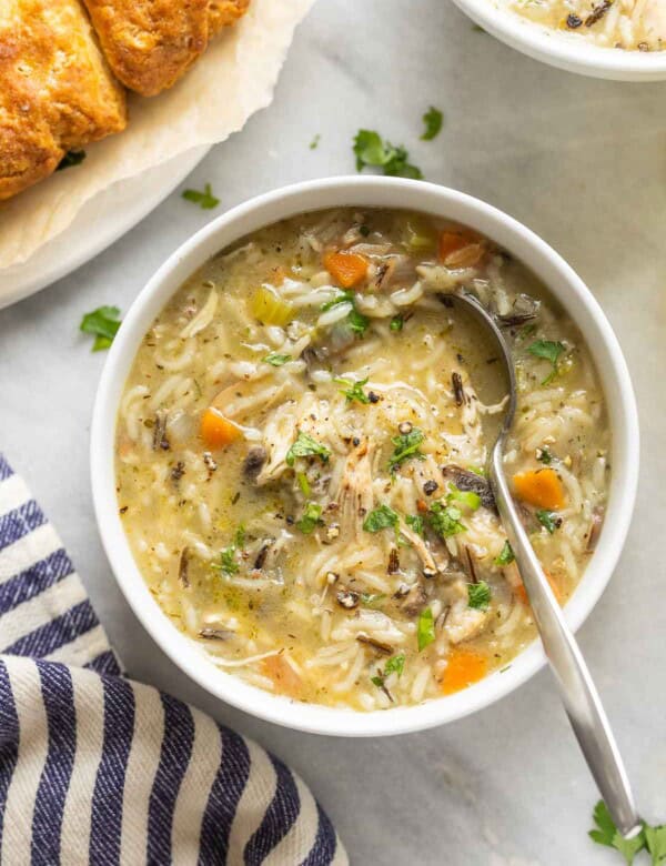 Instant pot chicken & wild rice soup in a bowl topped with fresh chopped parsley and bread on the side.