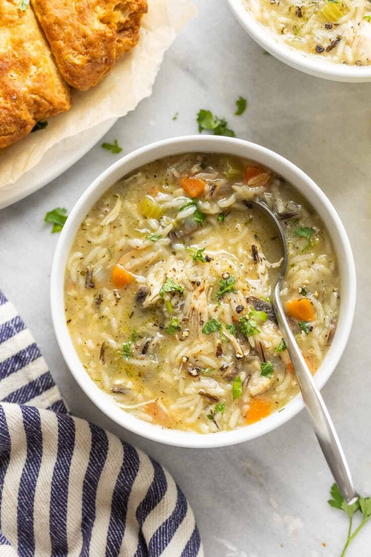 Instant pot chicken & wild rice soup in a bowl topped with fresh chopped parsley and bread on the side.