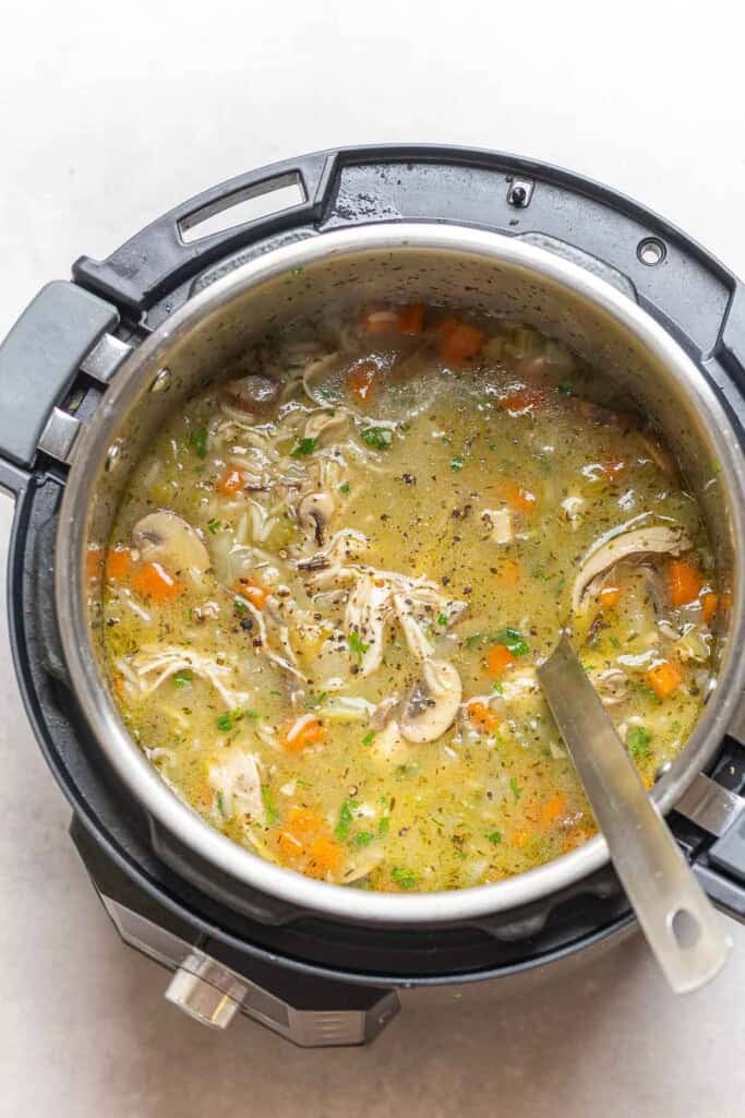 Instant pot chicken and wild rice soup with a soup ladle sitting in the pot.