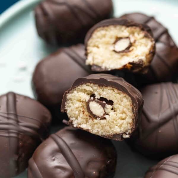 A homemade Almond Joy Snack Bites cut in half to show off the coconut almond filling with a chocolate covered almond hidden in the middle.