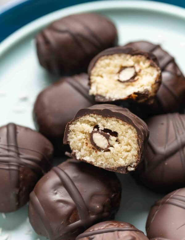 A homemade Almond Joy Snack Bites cut in half to show off the coconut almond filling with a chocolate covered almond hidden in the middle.