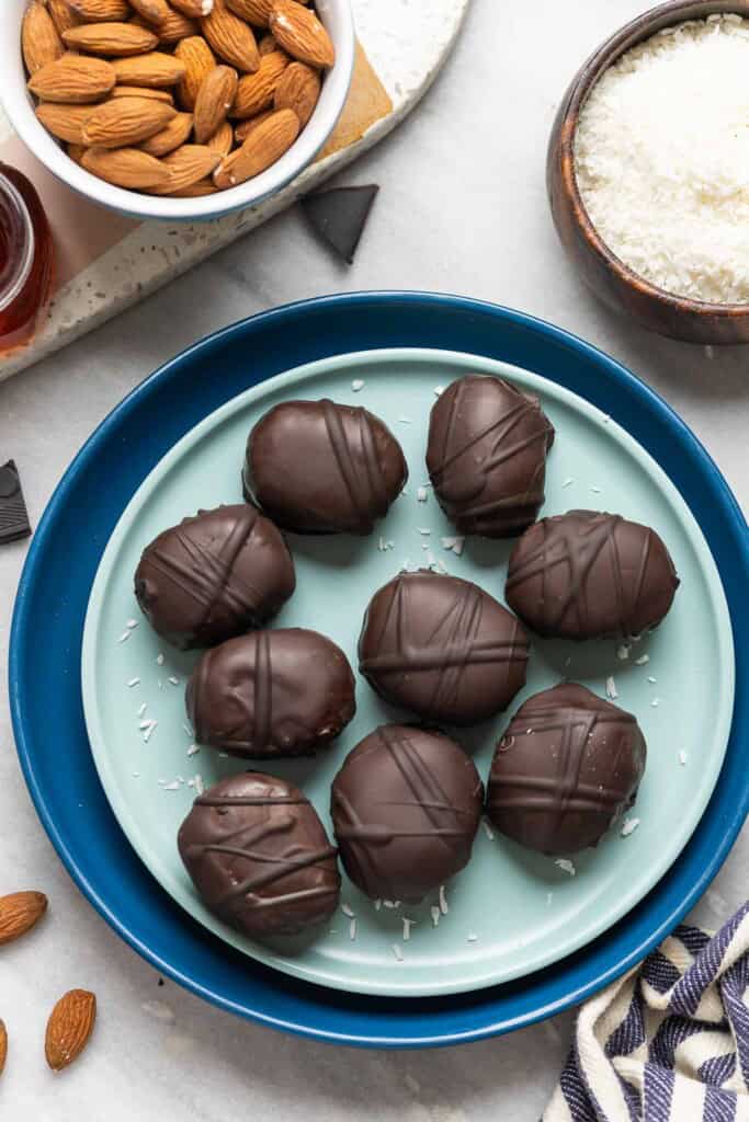 A plate full of healthy homemade almond joy snack bites covered in chocolate.