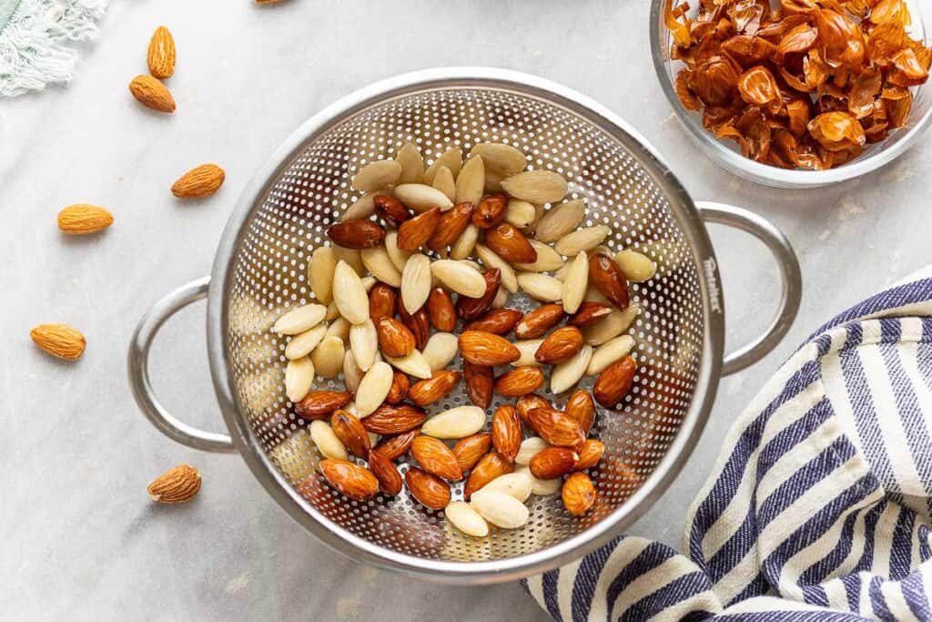 Boiled almonds in a colander in the process of getting blanched (removing the skin)