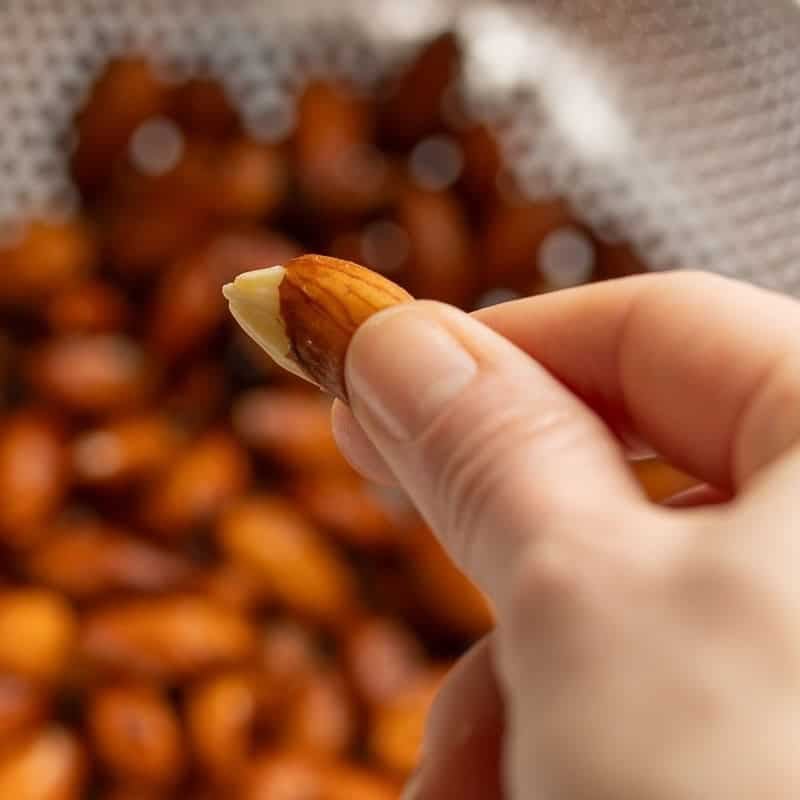 A freshly blanched almond getting pinched to remove the skin
