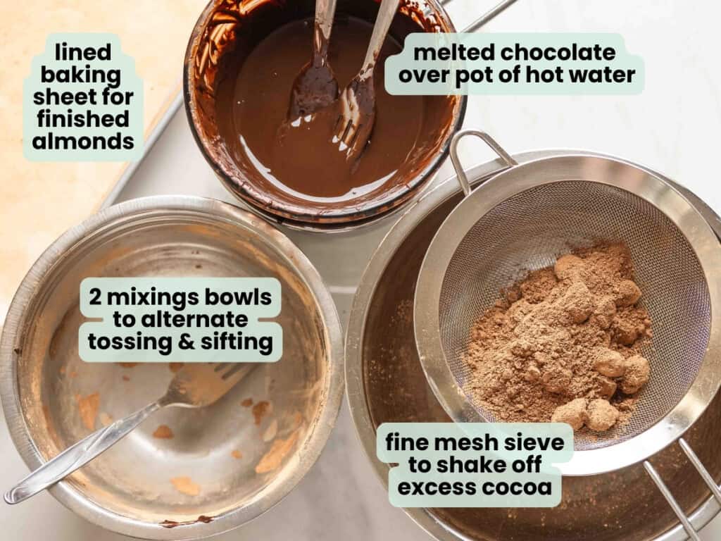 Tools needed to make these chocolate covered almonds: lined baking sheet for finished almonds, melted chocolate over pot of hot water, 2 mixings bowls to alternate tossing & sifting, fine mesh sieve to shake off excess cocoa