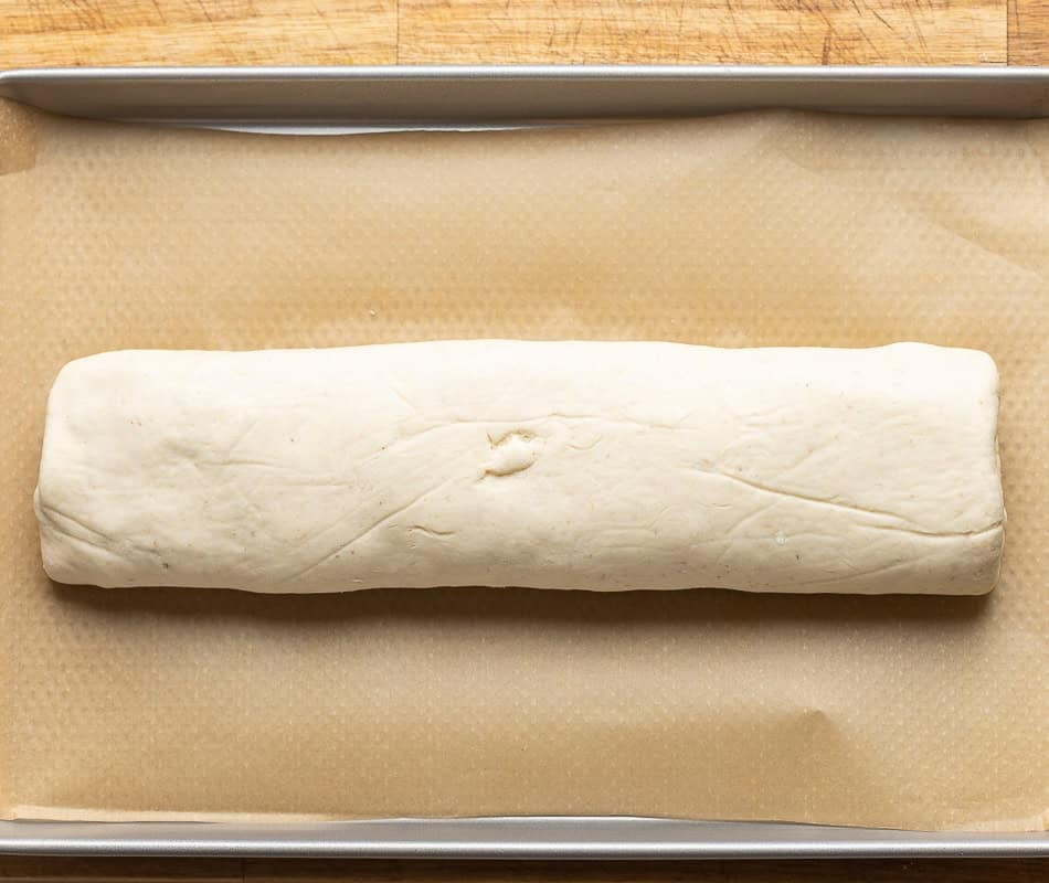 Unbaked gluten free stromboli log on a parchment lined baking sheet