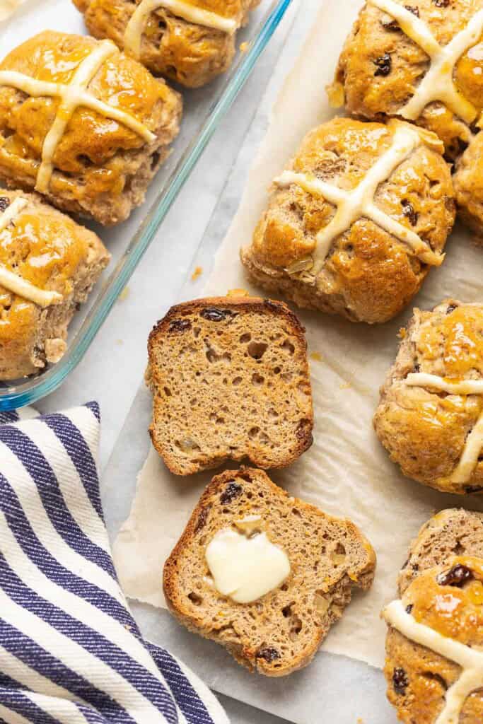 A toasted gluten free hot cross bun, cut in half with melted butter on top