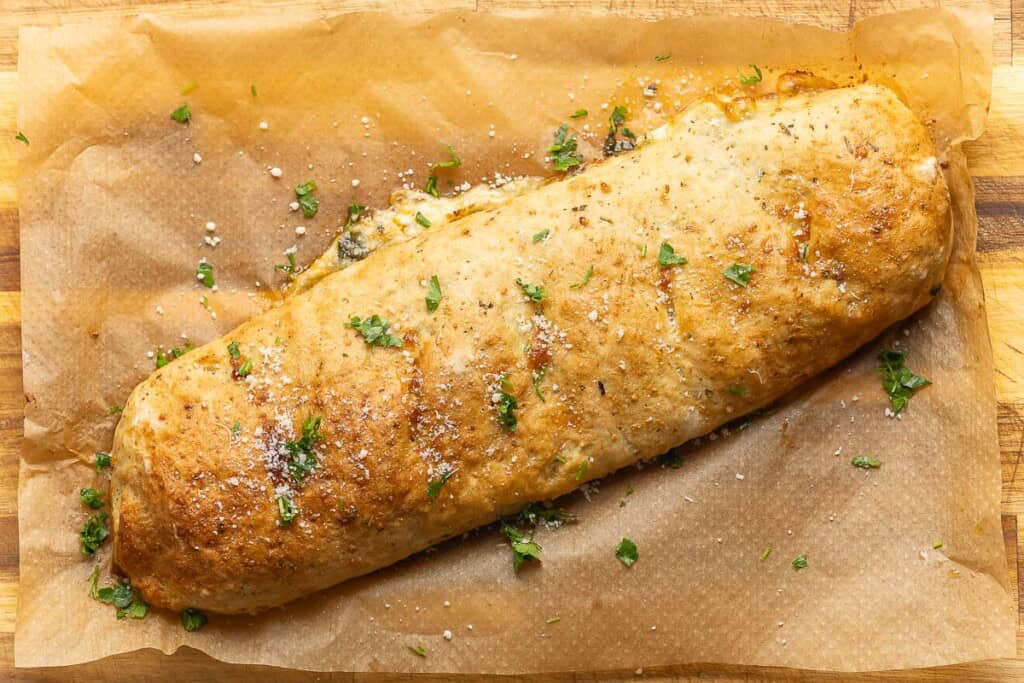 Gluten free stromboli on a with fresh chopped parsley and grated parmesan on top.