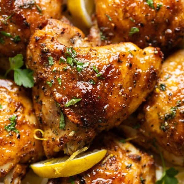 Lemon Pepper Chicken Thighs covered in a sticky lemon sauce with fresh chopped parsley and lemon slices