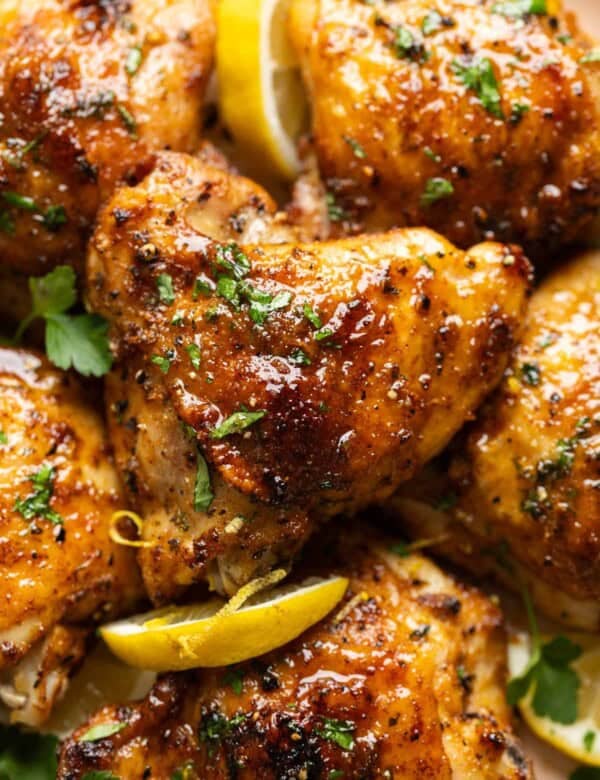Lemon Pepper Chicken Thighs covered in a sticky lemon sauce with fresh chopped parsley and lemon slices