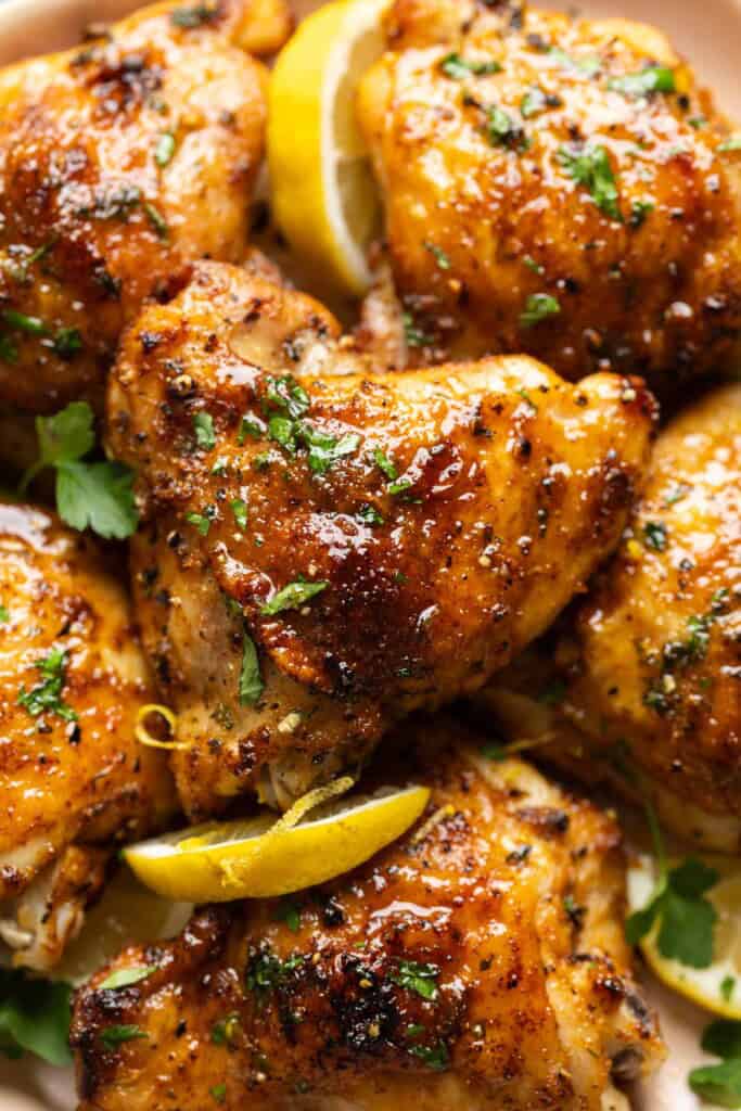 Lemon Pepper Chicken Thighs covered in a sticky lemon sauce with fresh chopped parsley and lemon slices