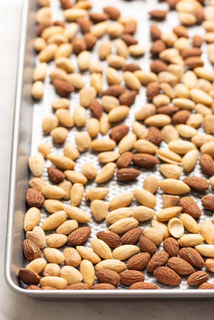 Blanched and unblanched roasted almonds on a baking sheet