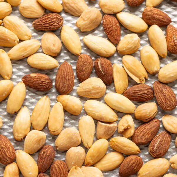 Blanched and un blanched roasted almonds on a baking sheet