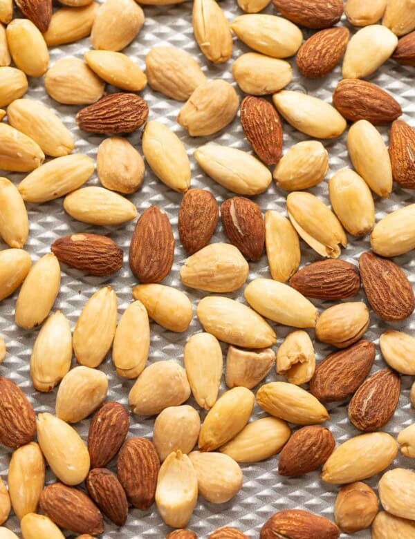 Blanched and un blanched roasted almonds on a baking sheet