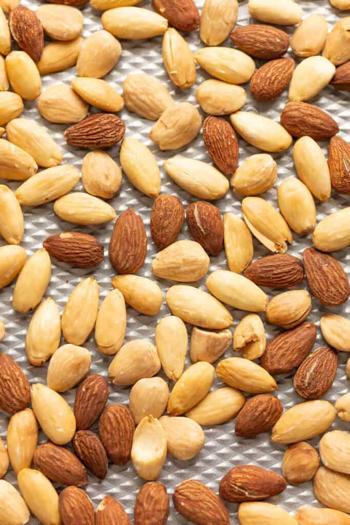 Blanched and un blanched roasted almonds on a baking sheet