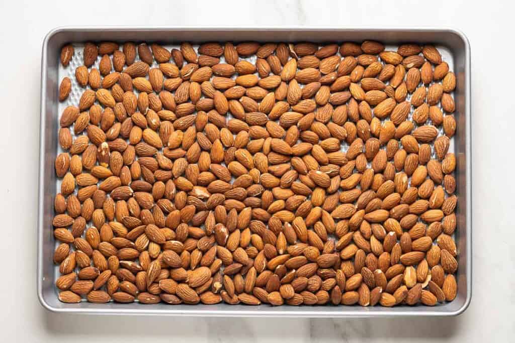Roasted almonds spread across a large baking sheet.