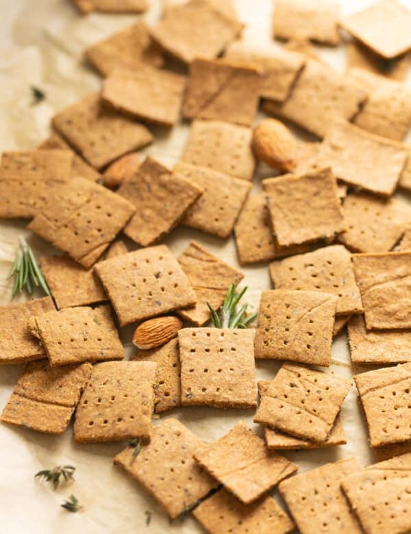 Homemade almond pulp crackers with scattered bits of rosemary, thyme and almonds.