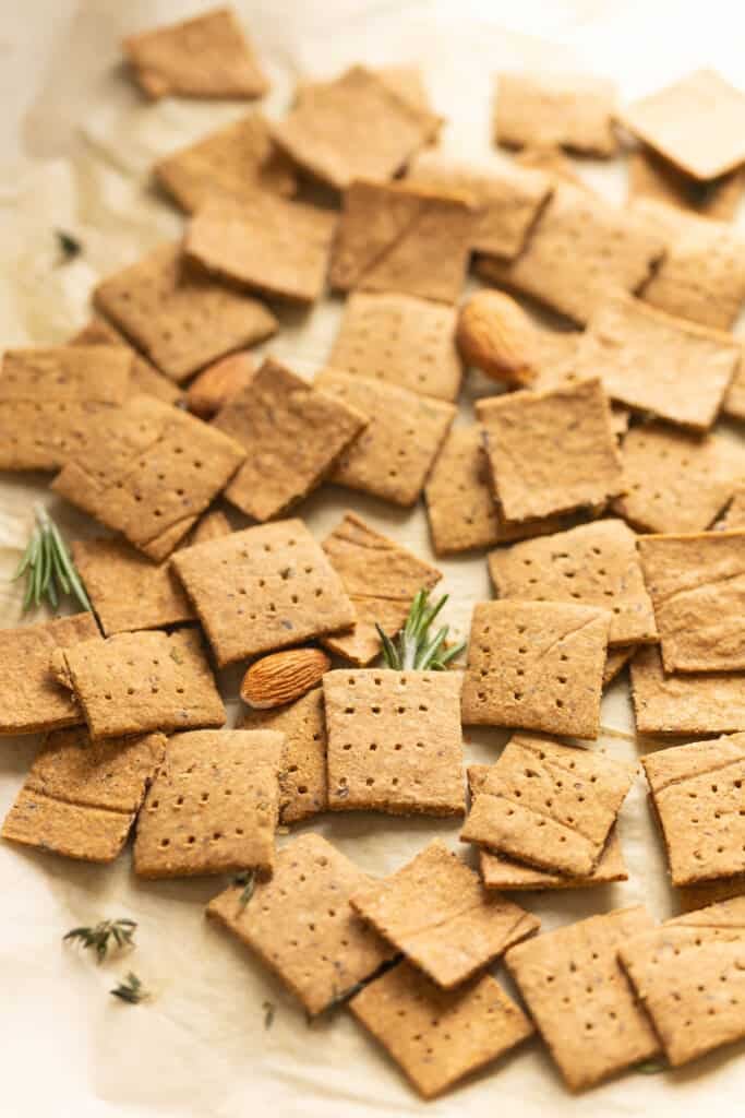 Homemade almond pulp crackers with scattered bits of rosemary, thyme and almonds.