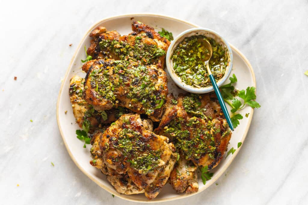 Grilled Chimichurri Chicken on a plate with a little bowl of extra chimichurri to top the chicken