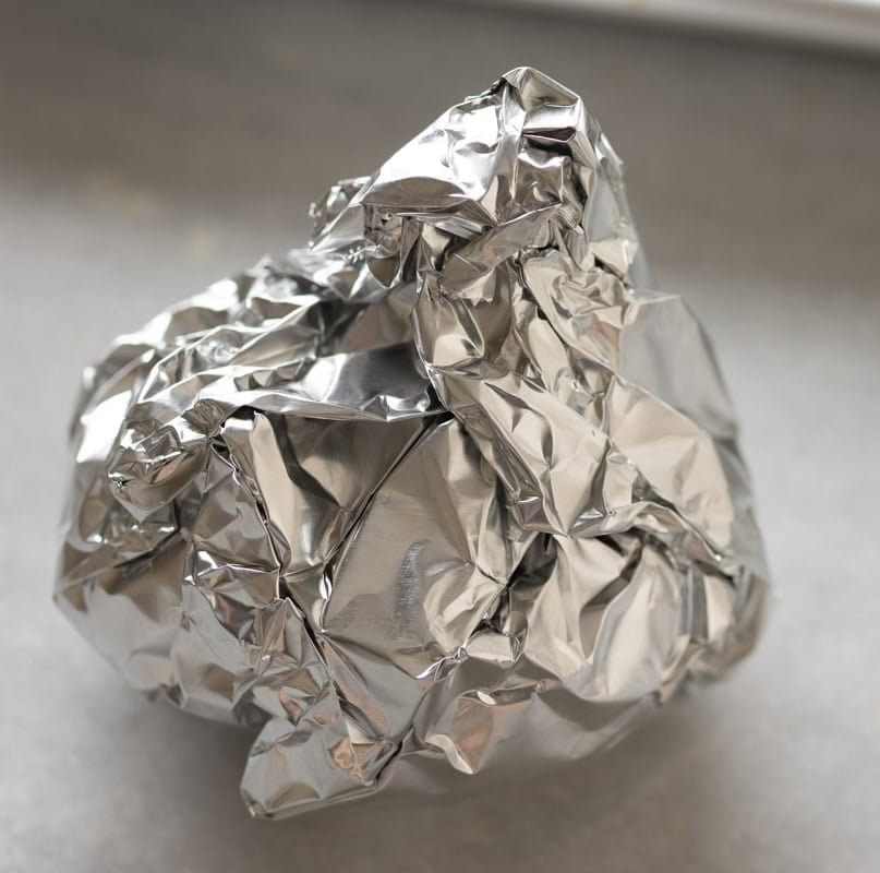 A head of garlic wrapped up in parchment paper and foil