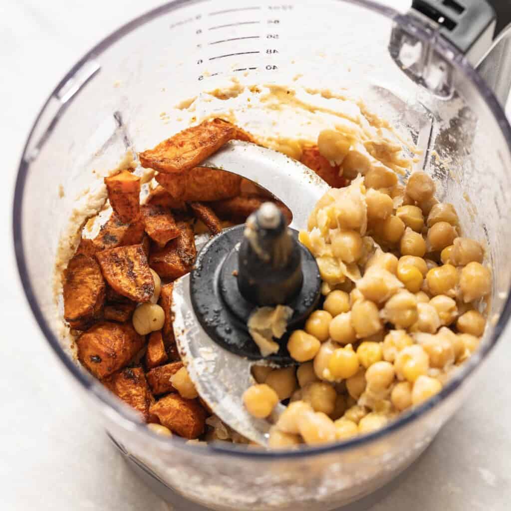 Roasted carrots and chickpeas added to a food processor with whipped tahini