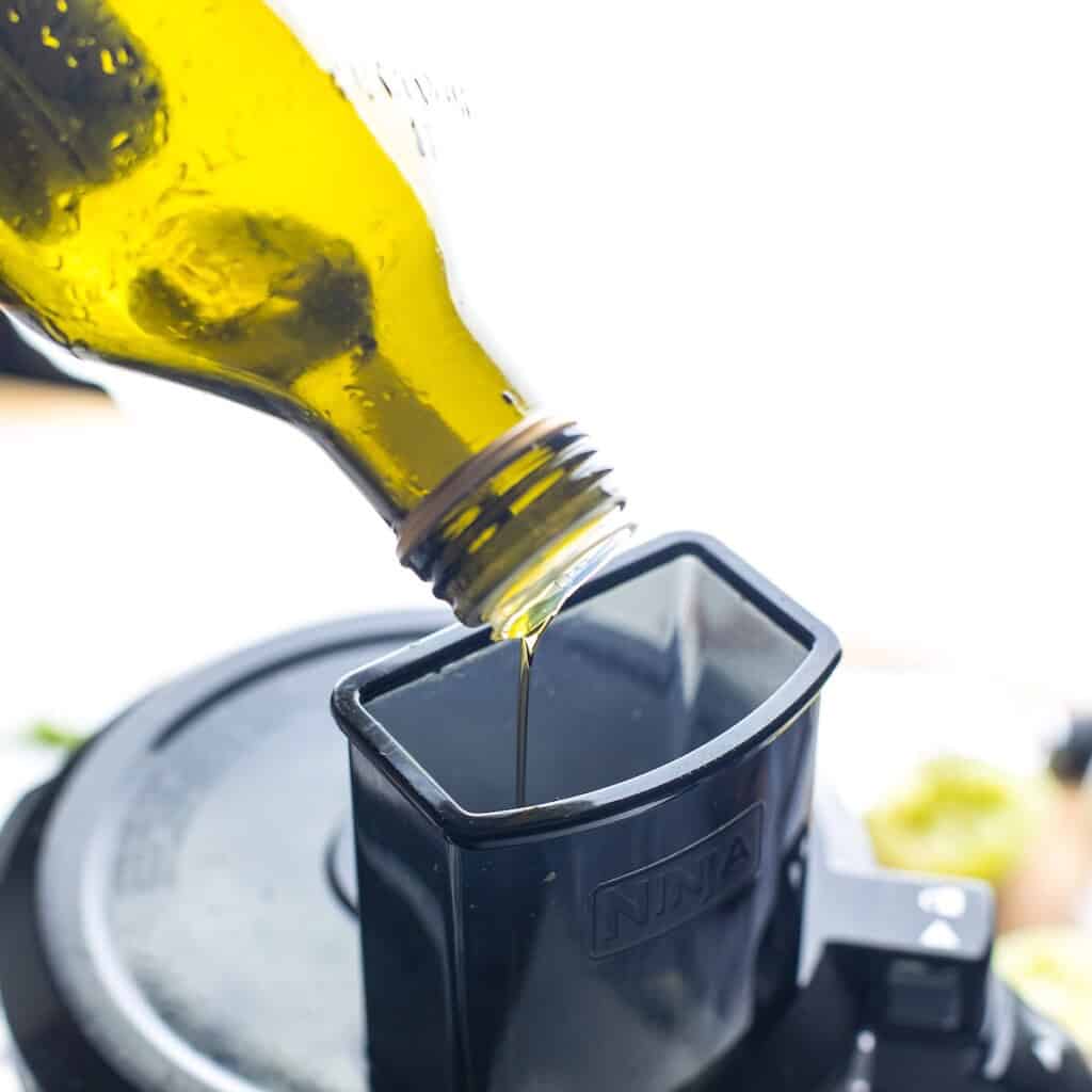 Olive oil slowly pouring into a food processor