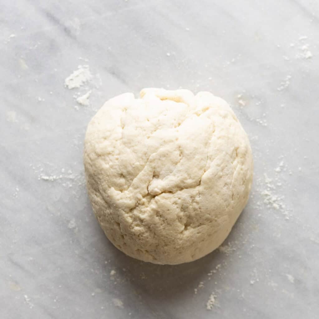 gluten free naan dough gently shaped into a ball on a lightly floured surface
