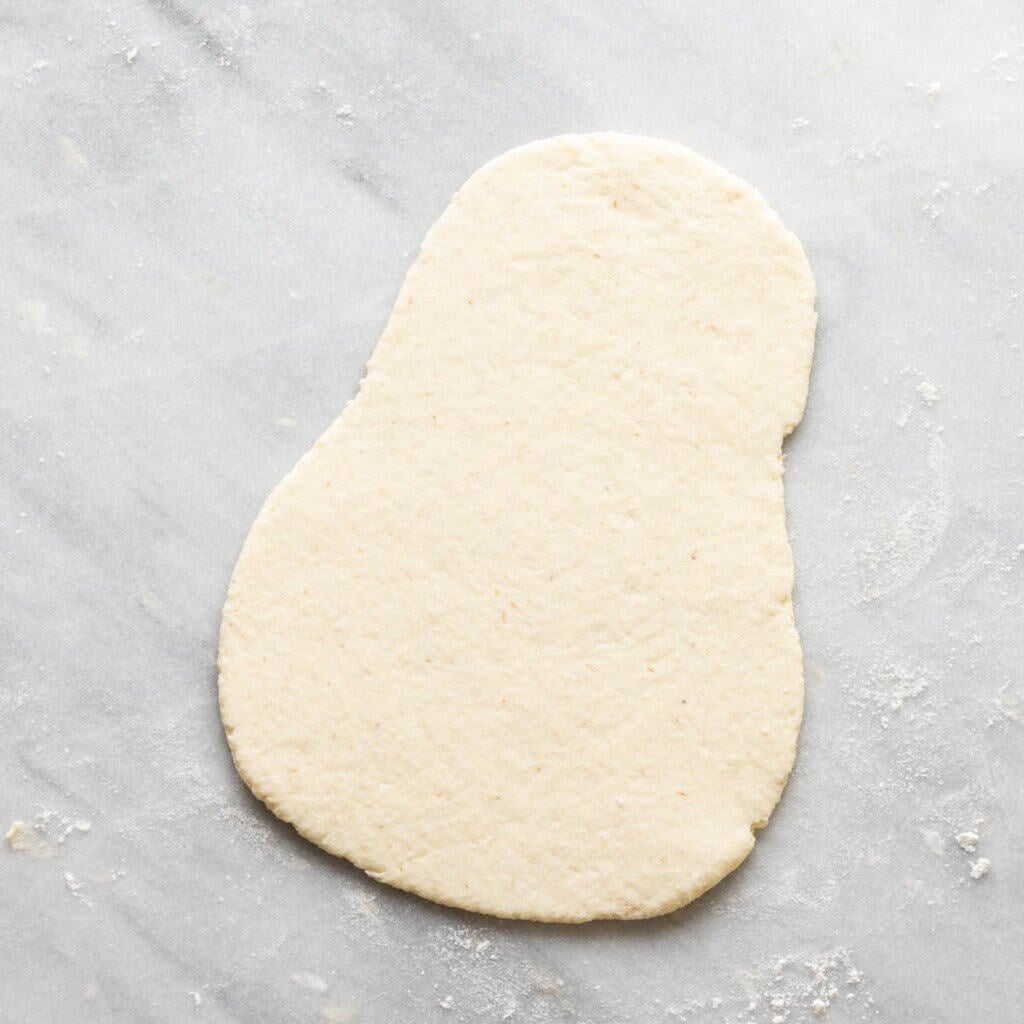 gluten free naan dough rolled out on a lightly floured surface, shaped like a butternut squash