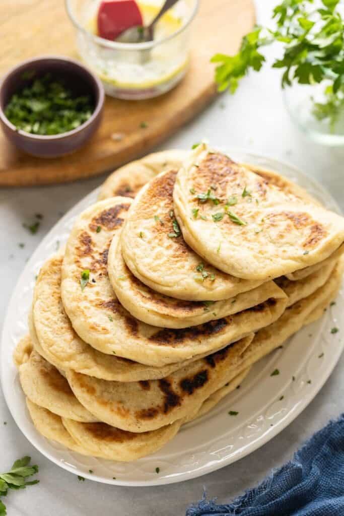 A stack of Gluten free naan folded over each other topped with with fresh chopped cilantro