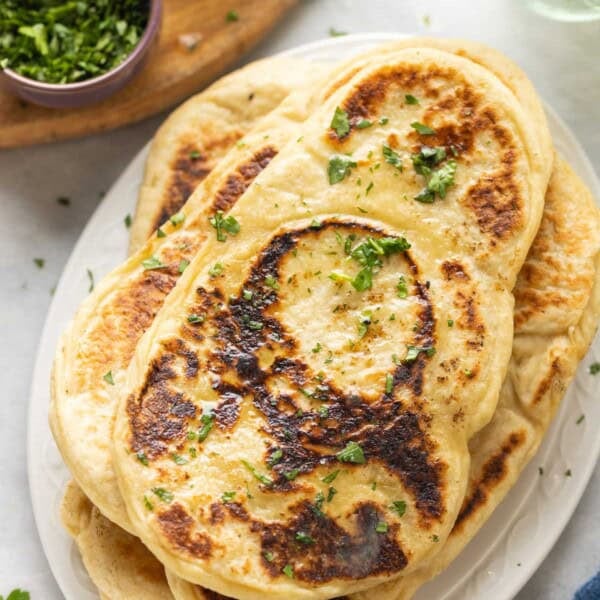A stack of Gluten free naan with fresh chopped cilantro on top and in a small bowl on the side
