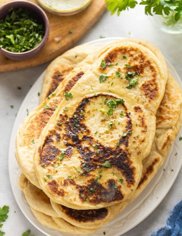 A stack of Gluten free naan with fresh chopped cilantro on top and in a small bowl on the side