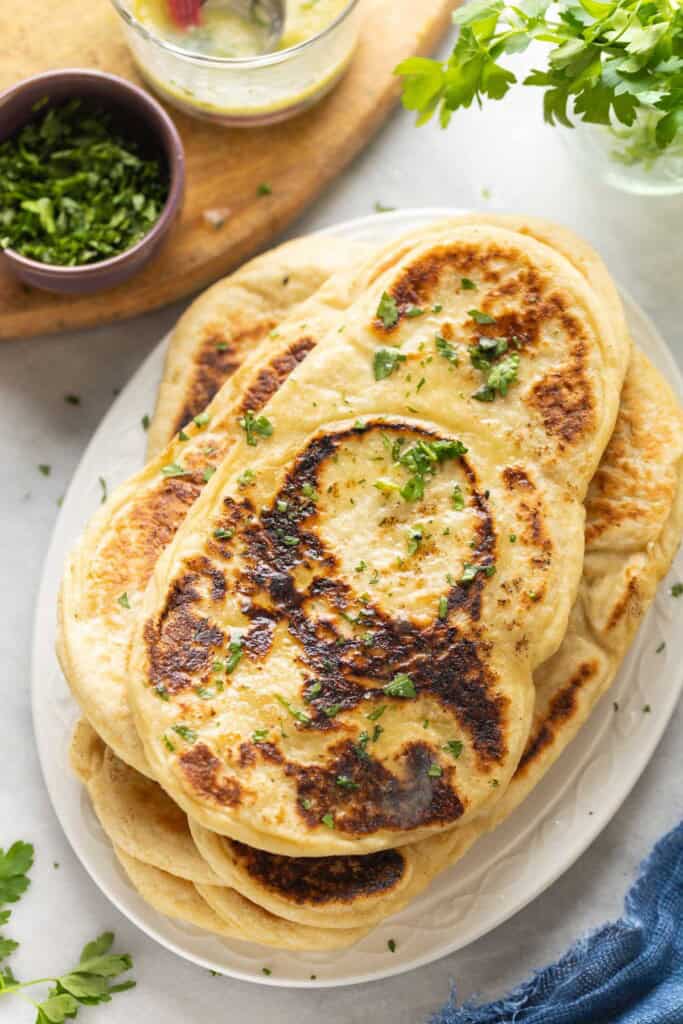 A stack of Gluten free naan with fresh chopped cilantro on top and in a small bowl on the side