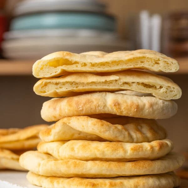 A stack of six homemade gluten free pita bread with a the top pita cut in half