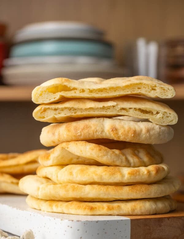 A stack of six homemade gluten free pita bread with a the top pita cut in half