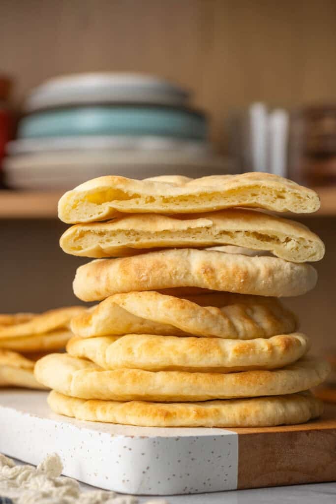 A stack of six homemade gluten free pita bread with a the top pita cut in half