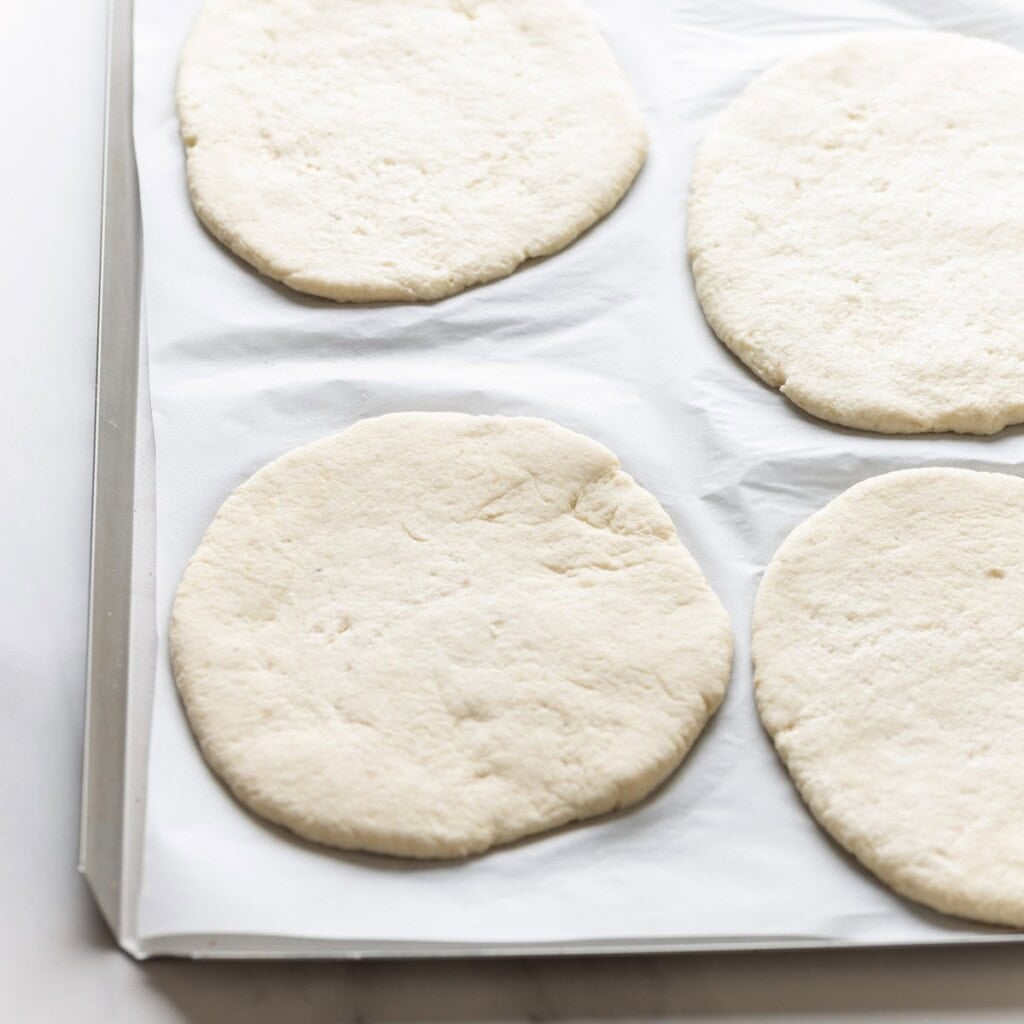 gluten free pita dough rolled into circles & resting on a baking sheet