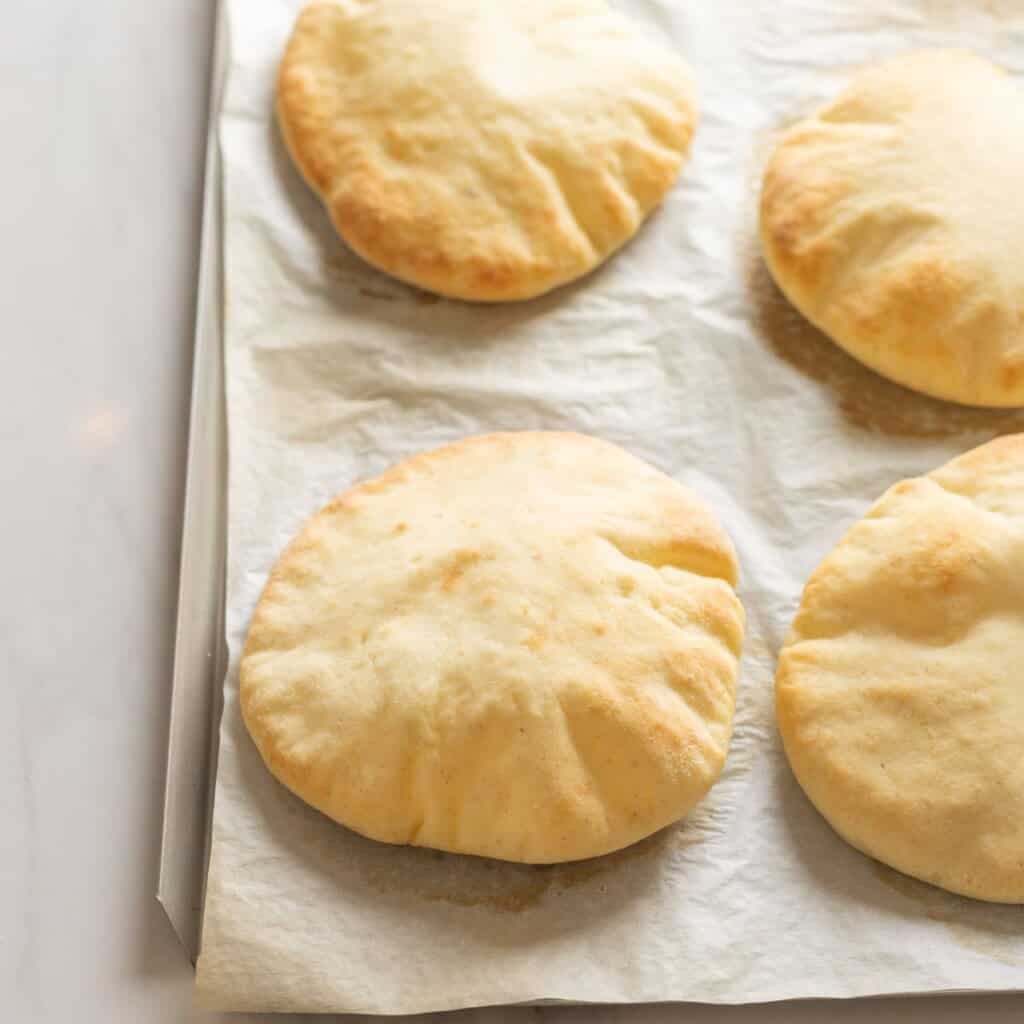 puffed up gluten free pitas on a baking sheet