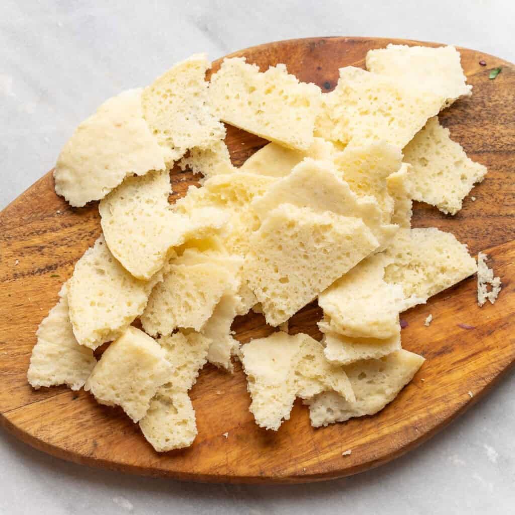 gluten free pita torn into chunks on a cutting board