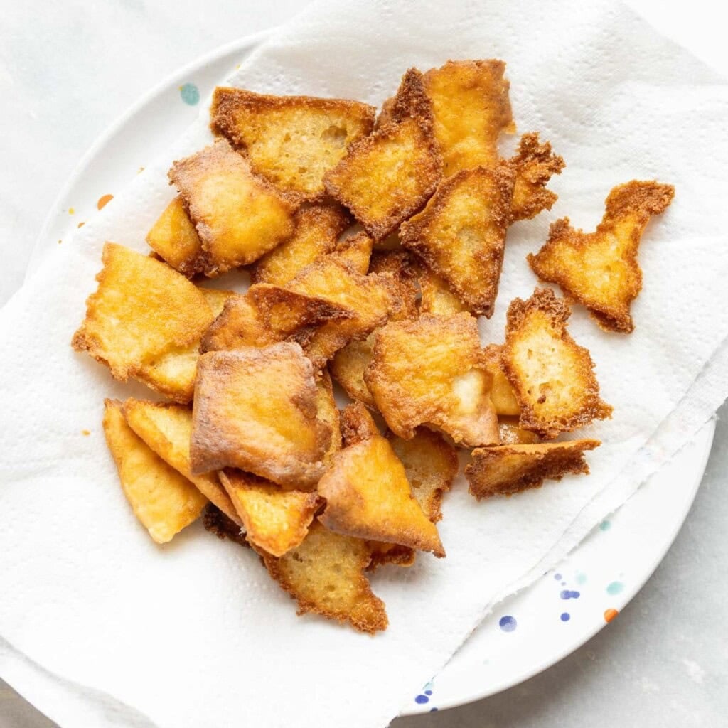 fried gluten free pita chips cooling on a paper towel lined plate