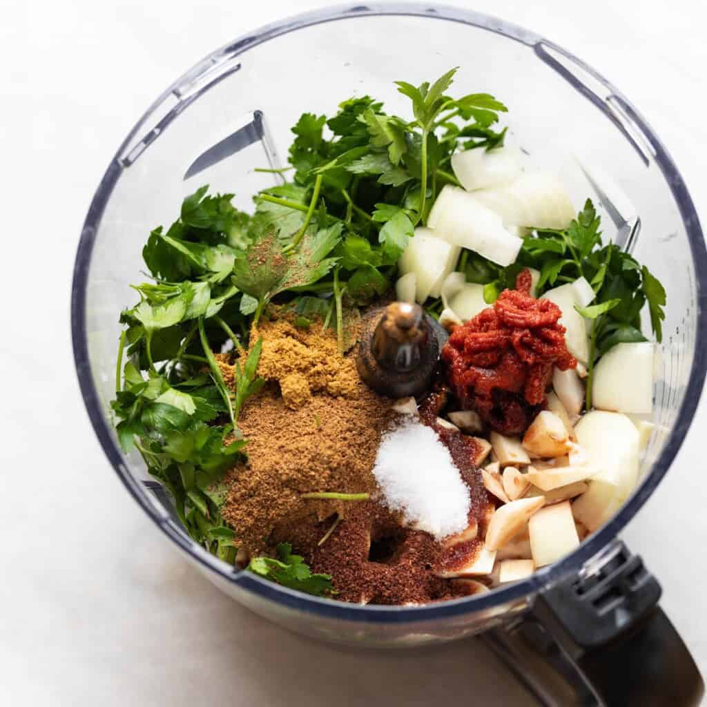 Chopped onion, garlic, parsley, spices, tomato paste and pomegranate molasses in a food processor.