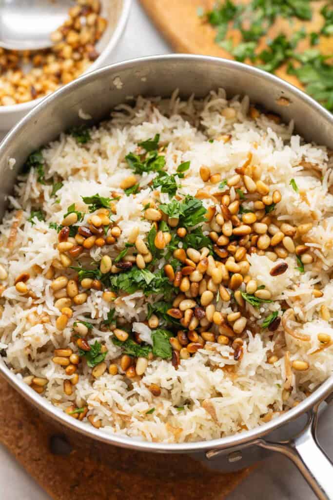 Lebanese rice made with gluten free noodles, toasted pine nuts and fresh chopped parsley in a sauce pan.