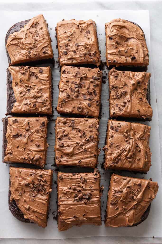 9x13 inch gluten free Chocolate Zucchini Cake with chocolate buttercream frosting and chocolate curls on top, cut into 12 pieces