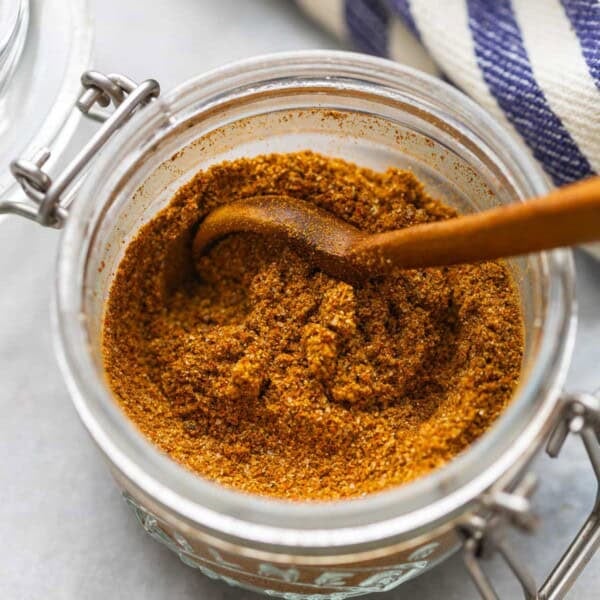 Homemade Shawarma Spice Blend in a small storage jar with a wooden spoon.