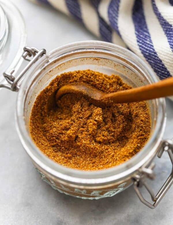 Homemade Shawarma Spice Blend in a small storage jar with a wooden spoon.